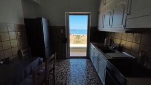 Una cocina con vistas a la playa, un refrigerador, un lavamanos y un comedor.