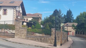 A street with stone buildings, a paved sidewalk, and a curved road. - El Rincon de San Fermin (Zizur Mayor)