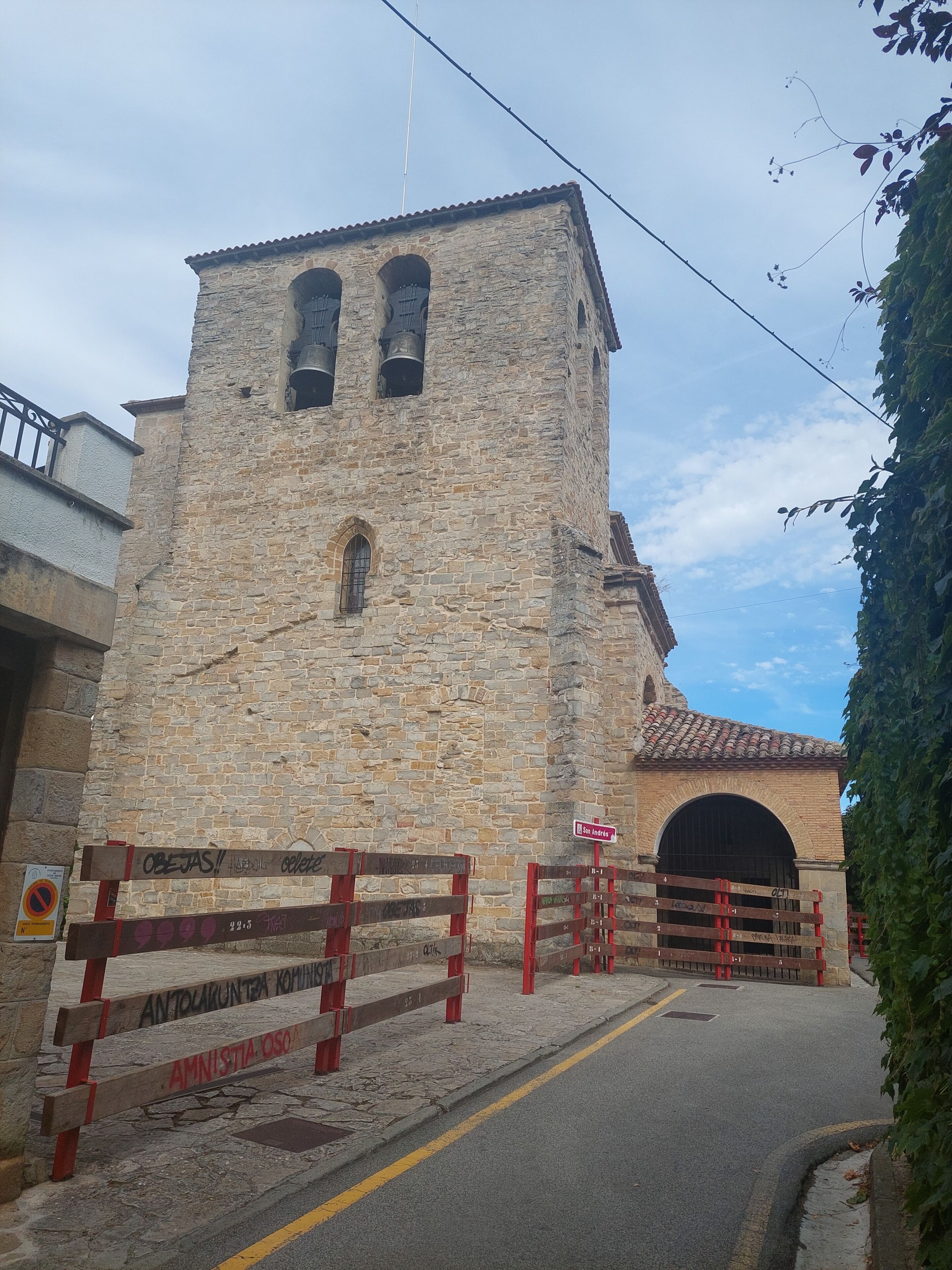 A stone building with a tower, a gate, and a street sign.