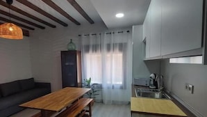 A modern kitchen with a wooden table and bench, a sofa, and a dining area. - El Rincon de San Fermin (Zizur Mayor)