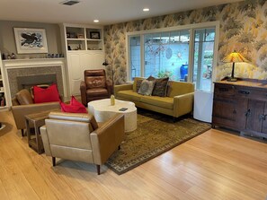 A living room with a fireplace, leather armchairs, a sofa, a coffee table, and a patterned rug.