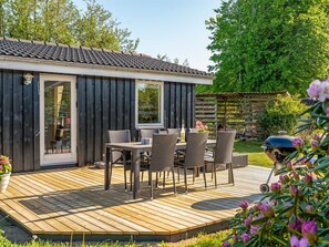 A wooden deck with outdoor furniture, a small building with a tiled roof, and a garden area. - "Stefana" -  from the sea by Interhome (Hals)