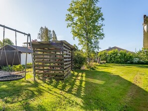En trækonstruktion med et lægter tag, en gyngestativ og en velholdt græsplæne.