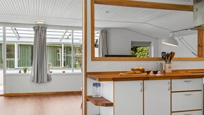 Een moderne keuken met een grote spiegel, houten planken en uitzicht op het groen.