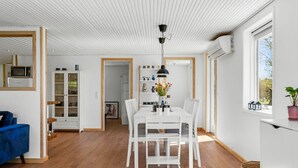 Een modern interieur met een eethoek, witte meubels en uitzicht door een raam.