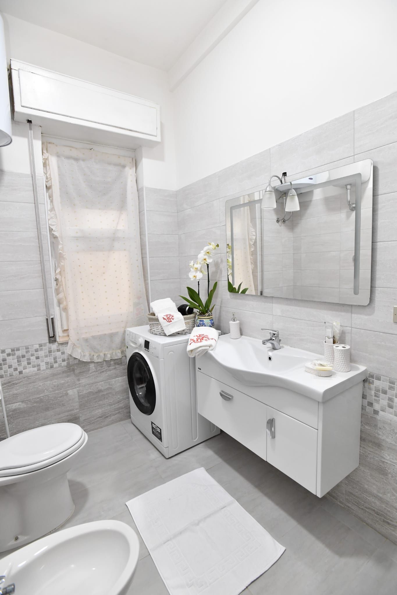 Un bagno moderno con lavatrice, lavandino e WC.