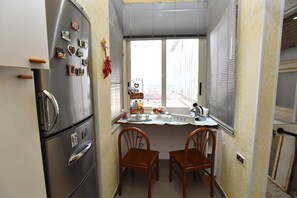 Una cucina funzionale con frigorifero, un tavolo da pranzo con sedie e una finestra con persiane.