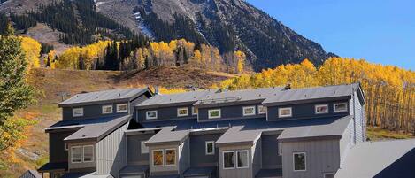 A multi-story building with a sloped roof, a covered outdoor area, and a mountain backdrop.