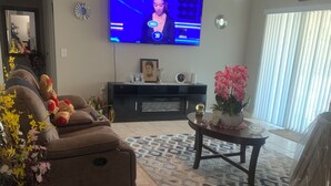 Ein Wohnzimmer mit einer Couch, einem Couchtisch, einem Fernseher und einem Deckenventilator.