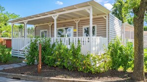 A single-story house with a covered porch, a small garden area with plants, and a wooden fence. - Tenuta Primero Grado Family Collection (Grado)