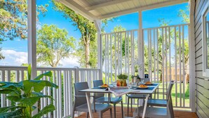 A covered patio with a table set for two, surrounded by chairs, a potted plant, and a small garden view. - Tenuta Primero Grado Family Collection (Grado)