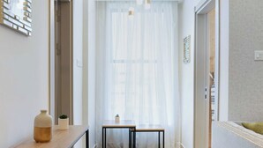 Un couloir moderne avec un plancher en bois, un tapis en fourrure, une table avec des chaises et un canapé.