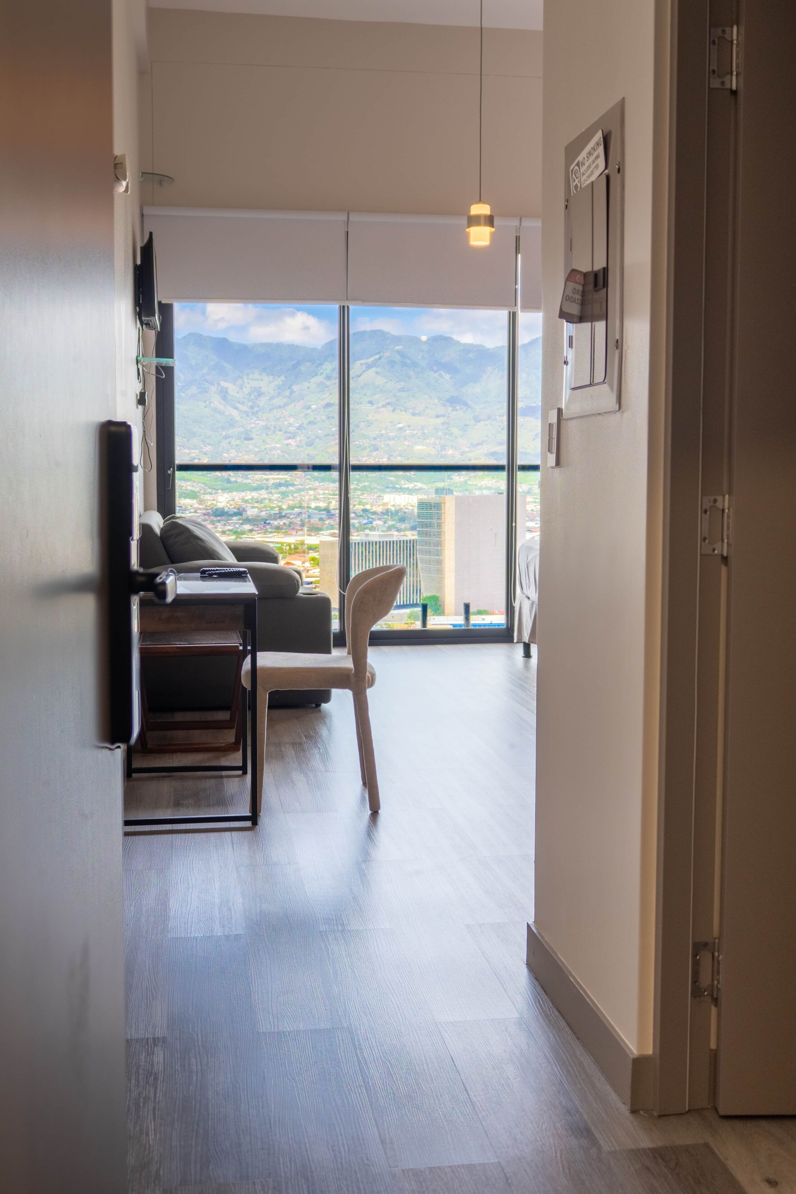 Une chambre d’hôtel moderne dotée d’un balcon, d’un canapé, d’un fauteuil et d’une télévision à écran plat.