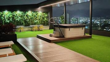 Une terrasse sur le toit avec un jacuzzi, des sièges extérieurs et une vue sur la ville.