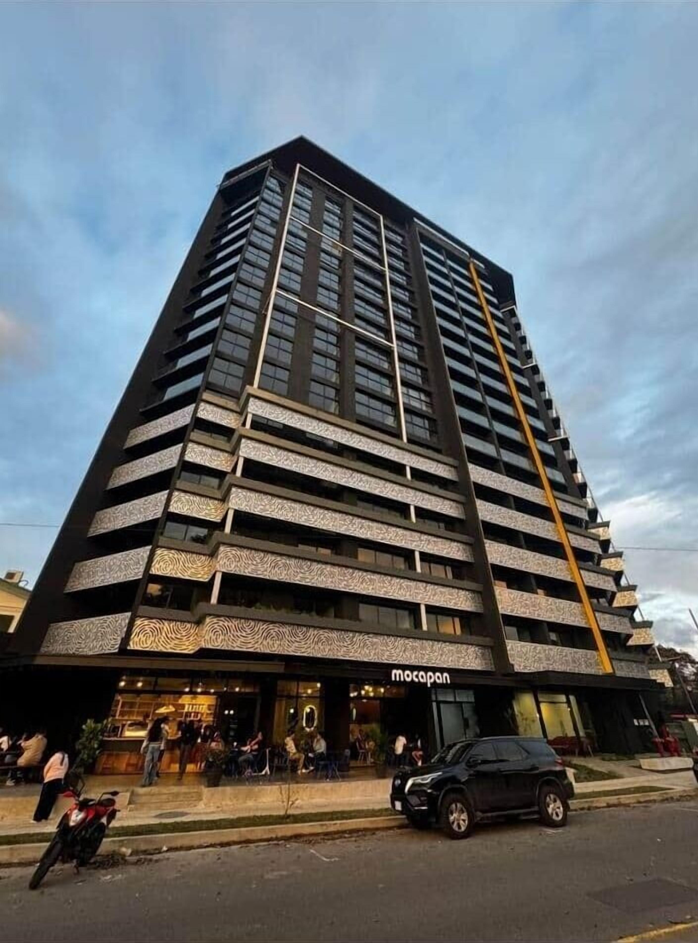 Un immeuble moderne et imposant, doté de nombreux balcons et d’une entrée remarquable.