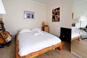 A bedroom with a bed, a guitar, a chessboard, and a poster on the wall. - Charming Apartment Near Buttes‑Chaumont and Belleville (París)