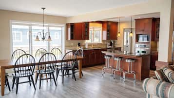 A spacious kitchen with wooden cabinets, a dining area with a wooden table and chairs, and a bar area with stools.