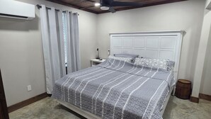 Een slaapkamer met een bed, plafondventilator en een airconditioning.