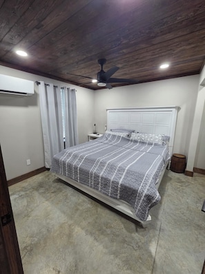 Un dormitorio con cama, ventilador de techo y aire acondicionado.