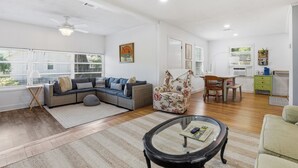 Amplia sala de estar con sofá, sillón, mesa de centro y comedor con mesa y sillas.