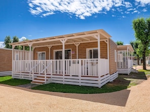 A wooden mobile home with a porch, white railings, and a number sign. - Tenuta Primero Grado Family Collection (Grado)