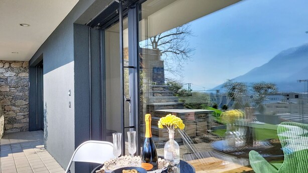 Ein Balkon mit Tisch, gedeckt für eine Mahlzeit, einer Champagnerflasche und einem Blumenstrauß.