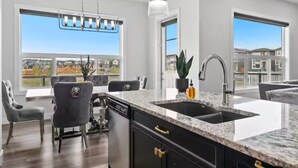 A modern kitchen with a large island, granite countertops, and a built-in dishwasher. - Cozy and Inviting home, whole house to your self to stay with 2 free parkings. (Calgary)