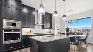 A modern kitchen with dark cabinetry, stainless steel appliances, and pendant lighting. - Cozy and Inviting home, whole house to your self to stay with 2 free parkings. (Calgary)