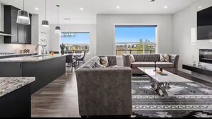 A modern kitchen with a central island, a dining area with a sofa, and a large window offering a view. - Cozy and Inviting home, whole house to your self to stay with 2 free parkings. (Calgary)