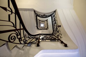 A spiral staircase with ornate metal railings and a white wall. - 50 Suite B&B (Naples)