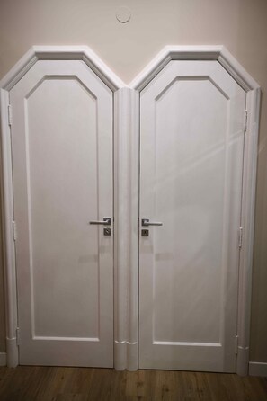 Um par de portas duplas brancas com design simples, uma fechadura e um puxador.