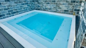 A square hot tub with a tiled border, surrounded by a wooden deck. - Ocean View | Central SD | Rooftop Plunge Pool (Santo Domingo)