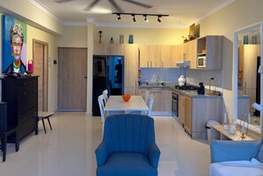 Eine moderne Küche mit Holzausstattung, einer weißen Arbeitsplatte und einem Essbereich mit blauem Stuhl und weißem Tisch.