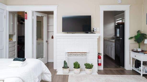 Ein Schlafzimmer mit Bett, Fernseher über einem Kamin und einem Schrank.