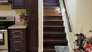 A kitchen with dark wooden cabinets, a stainless steel range, and a tiled floor. - Cozy 2BR Basement | Private Entry + Parking (Brampton)