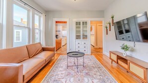 Una sala de estar con sofá, una mesa de centro, televisor y un mueble.