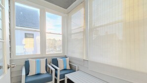 Un salón con ventanales, dos sillas, una mesa y vistas al exterior.