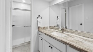 A bathroom with a large mirror, a sink, and a shower. - Bright 3BR/2BA Home  Furnished w/yard + All Utilities Included near Lake Houston (Humble)