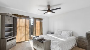 A bedroom with a bed, a wardrobe, a nightstand, a ceiling fan, and a window with curtains. - Bright 3BR/2BA Home  Furnished w/yard + All Utilities Included near Lake Houston (Humble)
