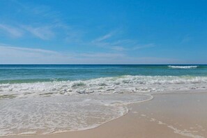 Een strand met golven, heldere lucht en een rustige zee.