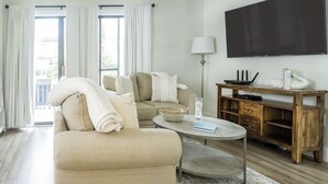 Un salon avec un canapé, une table basse, un téléviseur et une table d’appoint en bois.