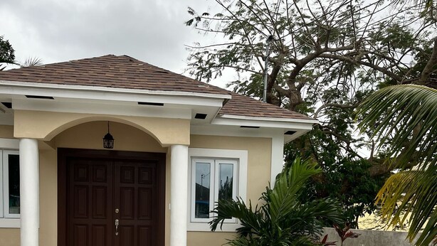 A house with a brown door, white columns, and a tiled roof. - Cozy 1-bedroom apartment in terrific Nassau with AC (Nassau)