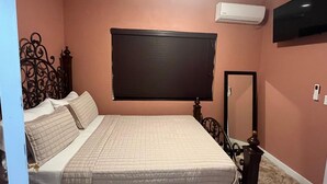 A bedroom with a bed, a TV, an air conditioner, and a mirror. - Cozy 1-bedroom apartment in terrific Nassau with AC (Nassau)