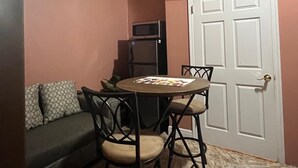 A compact living space with a ceiling fan, a television mounted above a door, a small dining table with chairs, and a sofa with cushions. - Cozy 1-bedroom apartment in terrific Nassau with AC (Nassau)