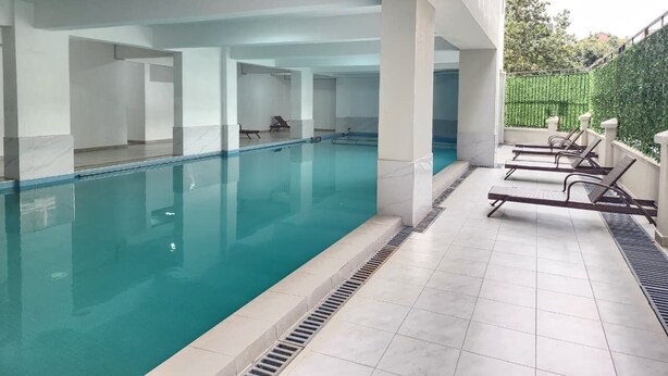 Ein Innenpool mit klarem Wasser, umgeben von weißen Säulen und einem gefliesten Boden.