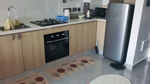 Eine moderne Küche mit Gasherd, Backofen, Edelstahl-Kühlschrank und Mikrowelle.