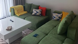 Ein grünes Sofa mit einem weißen Couchtisch, einer Fernbedienung und einer kleinen Tasche auf dem Tisch.