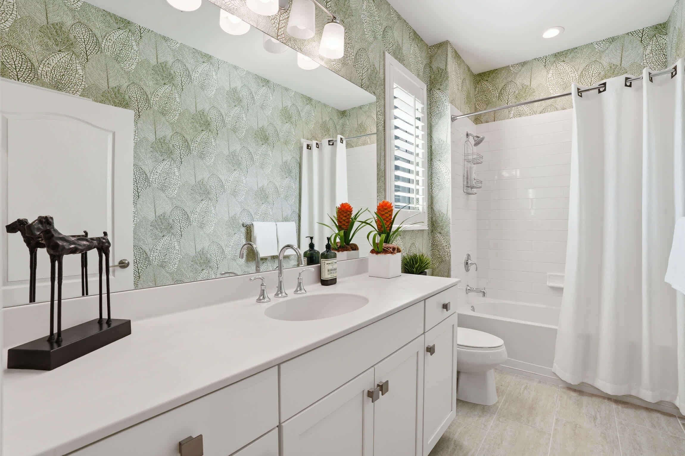 A bathroom with a large mirror, a sink, a toilet, and a shower area.