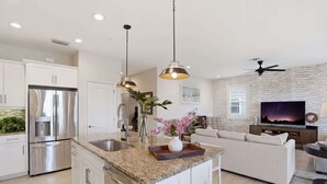 A modern kitchen with stainless steel appliances, a granite countertop, and pendant lighting. - Lakefront Luxury + Stunning Naples Sunsets (Naples)