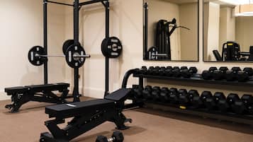 A gym with weightlifting equipment, including a squat rack, bench, and dumbbells.